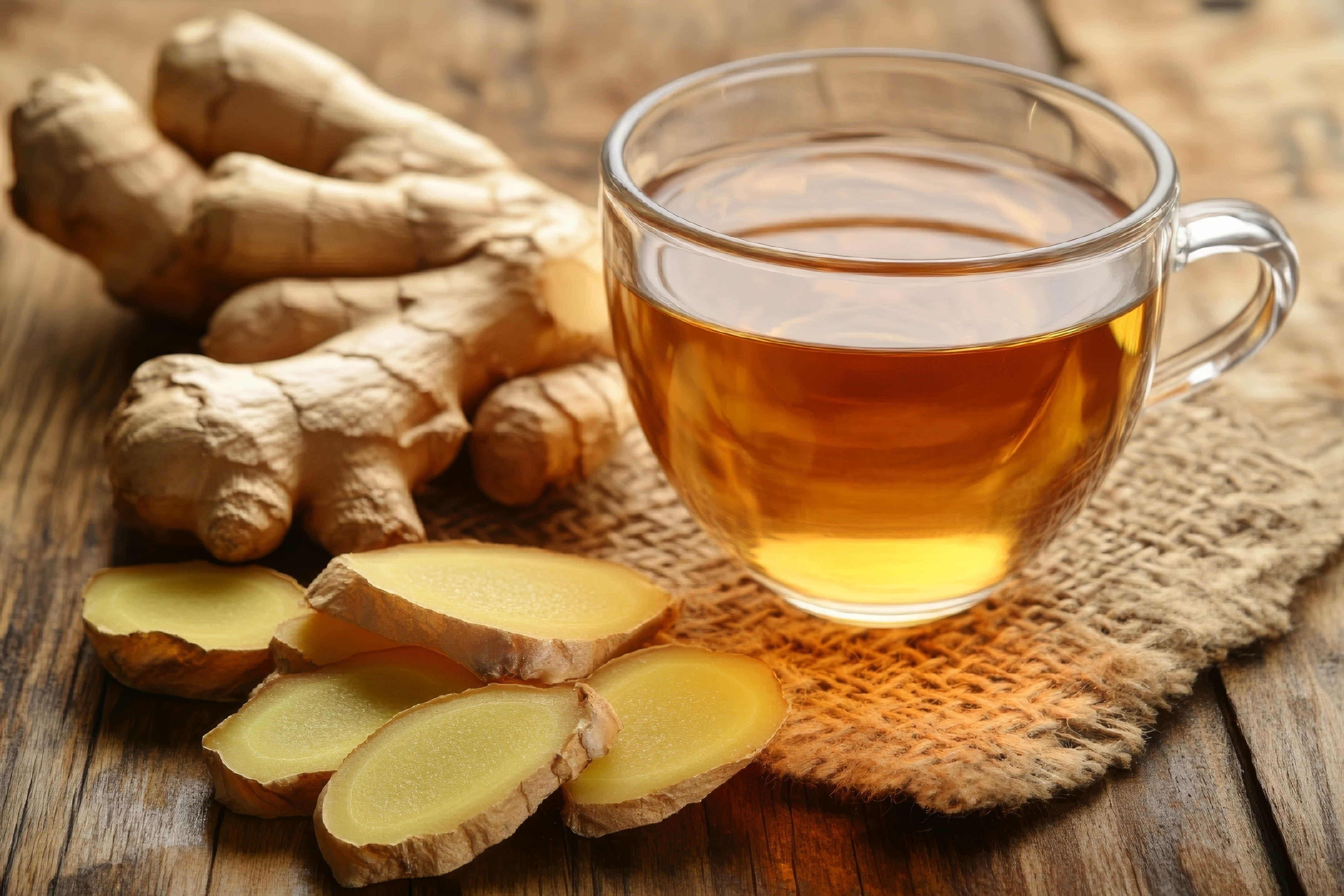 Brewed ginger tea and ginger root surrounding the glass cup